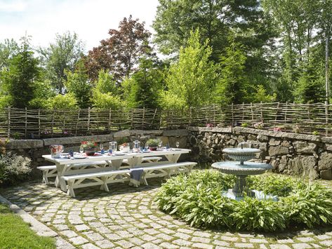 A Seaside Haven on the Kennebunk River - Decor Maine Classic New England Home, New England Backyard, White Picnic Table, Potted Plant Centerpieces, Stick Fence, Tiered Fountain, Lush Backyard, Wattle Fence, White Picnic