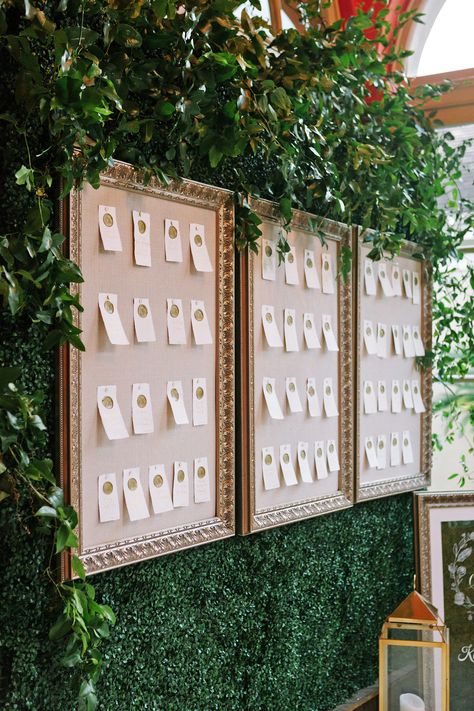 For the escort card display by Luminous Events, rectangular pieces of paper were attached to poster board inside of gold picture frames. The entire display was set against a background of greenery. "The escort cards were a stylish way to incorporate elements from the invitations," says Katherine. "The gold wax seal topped the handwritten gold calligraphy (by inLoft Calligraphy) on cream parchment paper." Boxwood Hedge Wall, Wedding Plants, Boxwood Hedge, Easy Backdrops, Seating Cards, Card Display, Greenery Garland, Custom Signage, Martha Stewart Weddings