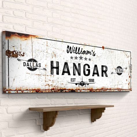 "Add a touch of personalization to your aviation decor with this custom hangar sign. Featuring your name, date and location, this rustic white sign is perfect for any pilot or aviation lover. Click here for more stunning Halloween and Gothic designs: https://www.etsy.com/shop/tailoredcanvases?section_id=35113001 Very Customizable  Custom-made! Print your name, family name, or anything at all! Send us ANY design request and we'll personalize it just for you!  About this canvas  1.25\" thick and d Aviation Theme Office, Pilot Lounge Decor, Aviation Themed Bedroom, Vintage Aviation Decor, Aviation Themed Room, Aviation Home Decor, Aviation Decor Interior Design, Aviation Office Decor, Hangar Decor