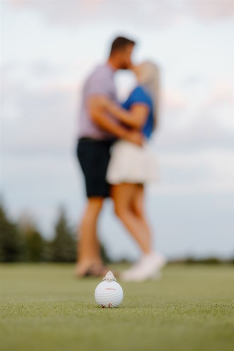 A pear-shaped engagement ring sits on top of a golf ball, a couple is blurred in the background kissing Golfing Couple Pictures, Golfing Engagement Photos, Mini Golf Engagement Photos, Golf Course Engagement Photos, Golf Photoshoot Photo Ideas, Golf Engagement Photos, Golf Photoshoot, Unique Engagement Photoshoot, Couples Golfing