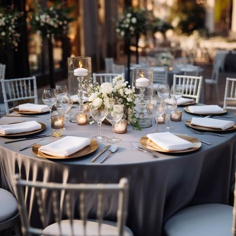 Amp up the elegance of your outdoor wedding space by setting up riveting tablescapes. Dress up the tables in a silver polyester tablecloth and arrange gold chargers, white napkins, gold cutlery, & wine glasses for a chic place setting. Ooze warm romantic glow by displaying gold mercury votive candle holders along with glass crystal cut candle holders gracefully placed inside glass vases. Create a stunning white hued rose & baby breath flower centerpiece to heighten the elegance of the tabletops. Silver Mercury Glass Centerpiece, Mercury Glass Centerpiece, Round Table Centerpiece, Wedding Votives, Baby Breath Flower, Event Decor Ideas, Party Decorations Table, Table Candles, Wedding Space