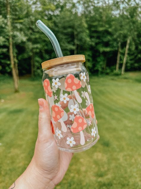 This trendy glass is the perfect vibe for the warmer weather! The glass pictured below is 16oz. All of our cups are made with permanent uv decals and come with a bamboo lid & reusable glass straw. All glasses are handwash only and come with care instructions in each package! This item is made to order and is not eligible for return. If you have any questions about your order, please reach out to us at bidwellbydesign@gmail.com. Pretty Glass Cups, Glass Bottle Design Ideas, Mushroom Glass Cup, Custom Cups Ideas, Glass Cups With Bamboo Lids Designs, Cute Glass Cup Designs, Cricut Glass Cups, Cute Glass Cups, Glass Cup With Straw