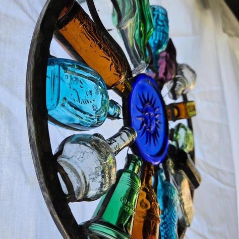 This is a one-of-a-kind glass art piece, fabricated using mini glass bottles that I had collected over the years. It was quite difficult to make - trying to problem solve making a 2-D piece from 3-D objects and have it structurally sound. It measures 11" in diameter, with a cast glass sun in the centre medallion, and a sturdy zinc frame. Mini Glass Bottles Ideas, Wine Bottle Fence, Bottle Glass Art, Recyclable Art, Glass Bead Crafts Diy, Bottles Wall, Glass Crafts Diy, Upcycled Bottles, Broken Glass Crafts