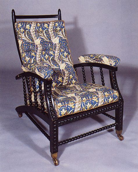 "Morris Chair", an adjustable back chair designed by Philip Webb for Morris, Marshall, Faulkner & Co., 1866. The design features a reclining back & moderately high armrests. The characteristic feature is a hinged back, with the reclining angle adjusted through a row of pegs, holes or notches in the arms. The original "Morris Chairs (pictured) had dark stained woodwork, turned spindles & heavily decorated upholstery. Morris Chair, Chair Pictures, William Morris Art, William Morris Designs, Arts And Crafts Furniture, Art And Craft Design, Arts Crafts Style, British Art, Arts And Crafts Movement