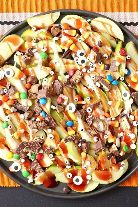 Put all that Halloween candy to good use by whipping up a tray of these dessert nachos. Top sliced Granny Smith apples with melted peanut butter, jelly, and chopped chocolate candy. A sprinkle of candy eyes adds a spooky touch. #halloweenrecipes #halloweentreats #halloweensnacks #halloweenpartyfood #bhg Halloween Potluck Recipes, Halloween Food Snacks, Halloween Potluck, Dessert Nachos, Halloween Finger Foods, Finger Foods For Kids, Halloween Charcuterie, Apple Nachos, Halloween Apples