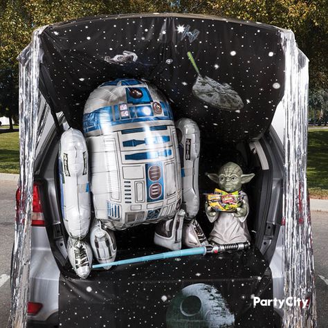 Take your car for a cruise—in a galaxy far, far away! No need to be a Jedi Master to create this this trunk-or-treat setup. This Star Wars-inspired idea gets help from R2D2 gliding balloon and a Yoda candy bowl holder. Place them against a backdrop of a starry night room roll adorned with decals. It’s no moon, but hanging silver door fringe on the side makes your “space station” ready for the fleet of trick-or-treaters. Halloween Car Decorations, Trunk Or Treat Ideas, Star Wars Halloween, Treat Ideas, Decorating Themes, Star Wars Birthday, Star Wars Party, Cool Themes, Trunk Or Treat