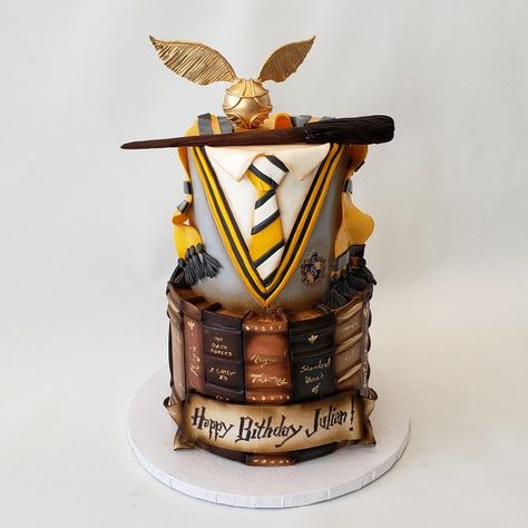 This Harry Potter 🎂 is casting a spell on Julian's Birthday! Edible golden snitch and wand top this cake covered in a Hufflepuff uniform. A library of spell books wrap the bottom tier with sugar parchment scroll. Hufflepuff Cake, Harry Potter Birthday Cake Hufflepuff, White And Gold Harry Potter Cake, Harry Potter Cake Quidditch, Hufflepuff Uniform, Harry Potter Cake 9 3/4, Hedgewig Owl Harry Potter Cake, Harry Potter Snacks, Hagrids Hut