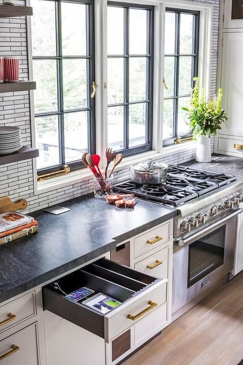 Black casement windows framed by gray mini marble backsplash tiles are positioned beside stacked wooden floating shelves and above a stainless steel oven range. Concrete Backsplash, Backsplash Herringbone, Honeycomb Backsplash, Backsplash Inspiration, Ikea Floating Shelves, Marble Tile Backsplash, Long Floating Shelves, Floating Shelves Bedroom, Reclaimed Wood Floating Shelves