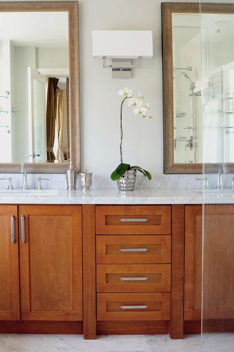 The grain of the moderate oak color vanities, combined with the fresh white marble top makes this bathroom a model of moderation. #darkcabinets #darkcabinet #darkcabinetry #whitecountertops #marblecountertops #whitecounters #whitemarblecounters #whitemarblefloor #marblefloor #whitefloor #marbletileflooring #marbletiles #oakcabinets #oakcabinetry #oakcupboard #shakercabinets #shakercabinetry #marblebacksplash #vanitycabinets #bathroommirrors #whitesink #porcelainsink #whiteporcelainsink Dark Bathroom Cabinets, Cabinets With White Countertops, White Marble Tile Bathroom, Shaker Bathroom, Shaker Bathroom Vanity, Light Grey Flooring, Oak Bathroom Cabinets, Dark Bathroom, Dark Wood Bathroom