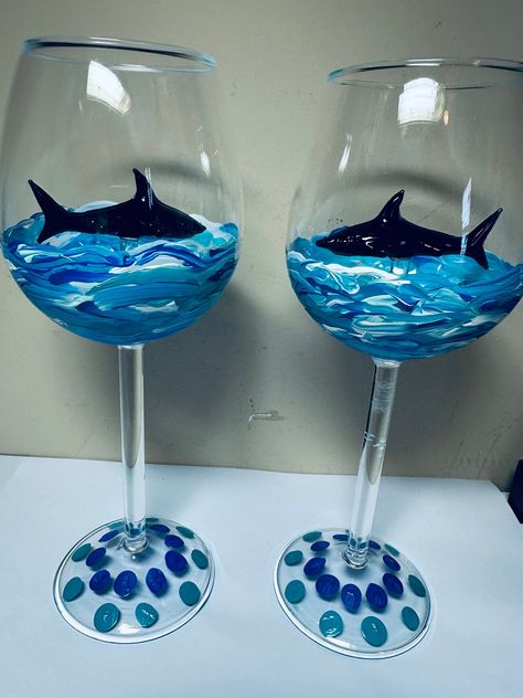 Hand Painted Stemmed Shark Wine Glasses with 3D Black Glass stemmed Shark inside surrounded by hand painted blue ocean. Each special glass is individually painted in similarity.  Great for any occasion, plus a beautiful decorative piece, giving you joy to your wine drinking experience. Use for Red, White, Rose or favorite drink for a touch of shark excitement. A one-of-a-kind gift for any occasion. Customized Requests are excepted using your favorite colors. Glass Shark available in clear, black, or pink. Dishwasher safe but NOT recommended. Handle with care, recommend gentle hand washing only. Beer Glass Painting, Glass Jar Painting Ideas Cute Easy, Wine Glasses Painted, Easy Wine Glass Painting Ideas, Painted Shot Glasses Diy, Paint Wine Glasses, Wine Glass Painting Ideas Easy, Glass Cup Painting Ideas, Wine Glass Painting Ideas