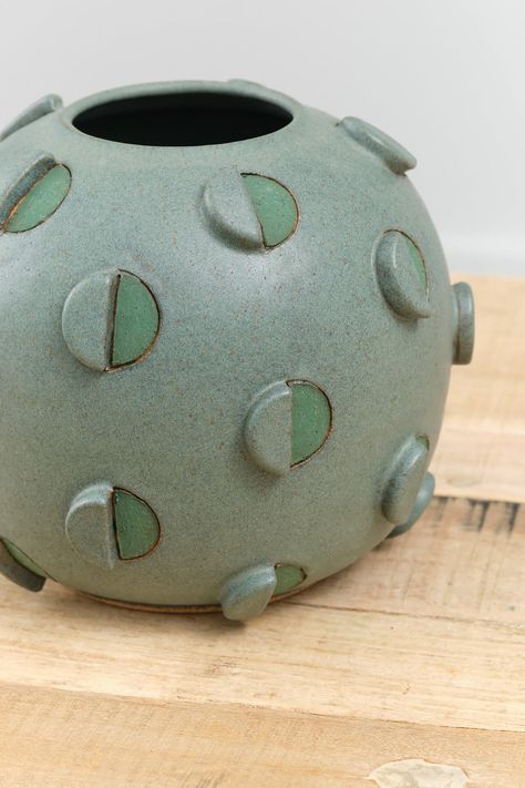 The Barrel Cactus Vase is a large decorative and functional bulbous vase with an abstract circle design throughout in a rich green glaze. Hand-carved and hand-painted geometric and three dimensional circle details adorn the exterior of the vase, finished with a Matthew Ward signature at the base. Ceramic Trends 2024, Soft Slab Ceramics Ideas, Ceramic Urns For Ashes, Ceramic Carving Designs, Ceramic Vase Ideas, Abstract Vases, Micro Sculpture, Geometric Pottery, Sculptural Vases