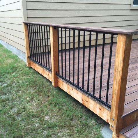 Rough-sawn western red cedar post, powder-coated black steel panel in between posts, deck board as a cap. Black Metal Porch Railing, Western Deck Railing Ideas, Hog Panel Porch Railing, Brown Deck Black Railing, Cow Panel Deck Railing, Porch Railing Diy, Wood Porch Railings, Log Home Deck Railing Ideas, Front Porch Railing Ideas