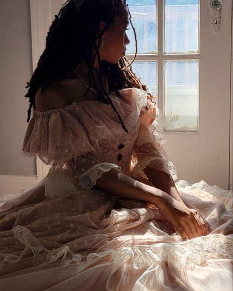 Close up shot of a girl—dressed in a champagne colored, off the shoulder ballgown with white polka tulle sleeves—sitting by and looking out the glass-pane windows on a white door. Light pouring in from behind Victorian Aesthetic Women, Black Victorian Woman Aesthetic, Ballgown Pose Reference, Victorian Aesthetic Clothes, Rich Victorian Aesthetic, Victorian Fantasy Aesthetic, Ballgown Pose, Victorian Black Women, Black Victorian Dress Aesthetic