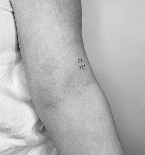 Above Back Of Elbow Tattoo, Minimalist Grandparents Tattoo, Simple Birth Year Tattoo, Year Dates Tattoo, Tiny Birthday Tattoos, Delicate Date Tattoo, Fine Line Year Tattoos, Small Tattoo For Parents, Creative Number Tattoo