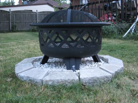 DIY - little rock pit for your fire pit. Put a plastic garbage bag over the grass, line the paving rock around it, fill the middle first with play sand, place the firepit in the sand, then cover the sand with marble chips. Make sure you are able to cover the entire bottom with the rocks. Made by my fiancee. Fire Pit On Rocks, Store Bought Fire Pit Ideas, Grass Fire Pit Area, Fire Pit On Grass, Fire Pit Base, Fire Pit Stand, Backyard Firepit Area, Trout Lily, Play Sand