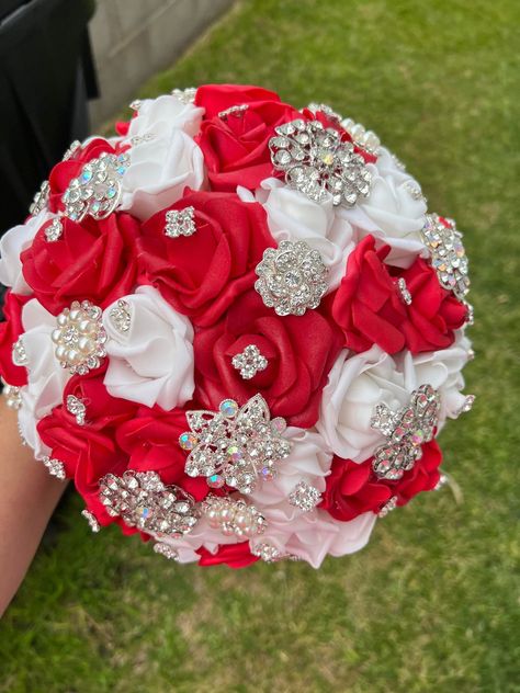 Handmade Quinceañera Bouquet/ Wedding. With Red and White Foamy Roses. Finished off with Silver brooches. *Please note brooches can change in style due to availability.* Decor / color combinations can be changed upon request. {This is a made to order Bouquet} Red And White Quince Bouquet, Red And Silver Flower Bouquet, Red Silver And White Wedding, Red White And Silver Quinceanera, Red Silver Wedding Theme, Bridal Bouquet Red And White, Red And White Quinceanera Decorations, Red And Silver Bouquet, Wedding Flowers Red And White