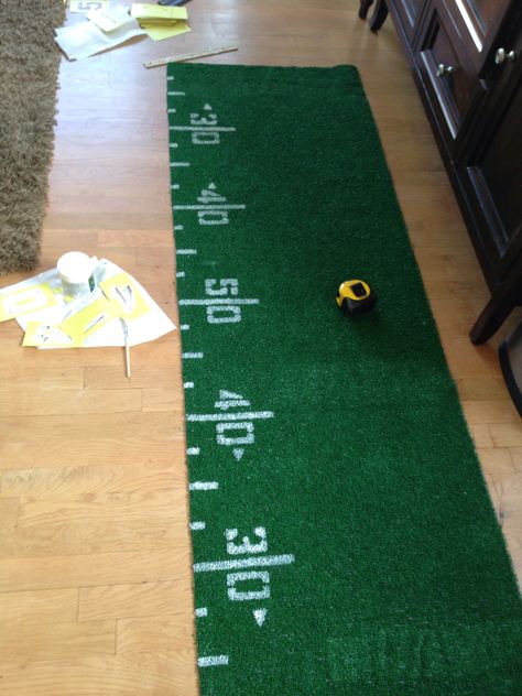 6ft Turf Table Runner for our Football theme grad party- for 4 football boys. Purchased 6x8 turf roll at Home Depot. Cut two 2x6ft pieces =4 runners. Stenciled numbers with regular white paint samples every foot and then added hash marks. Easy and should make a great piece for each of their tables. Turf Table Runner, Graduation Table Centerpieces, Football Banquet, Graduation Tables, Number Stencils, Football Themes, Football Birthday, Football Party, Office Parties