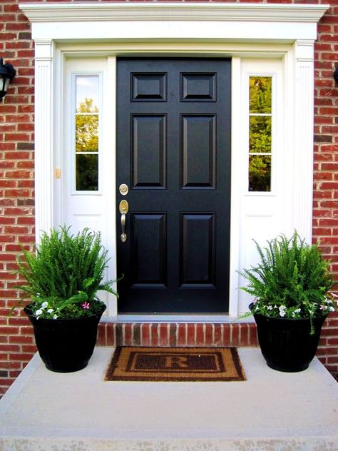 One of the best looks for your front porch is a simple symmetrical one. Get the same pots, flowers, and other items for your porch and then use the door as the divider. Simple and very classy. Use pots that look ancient and antique. It will add... Front Porch Flower Pots, Front Door Plants, Front Door Planters, Front Porch Plants, Black Front Door, Front Porch Flowers, Front Porch Planters, Door Planter, Porch Plants