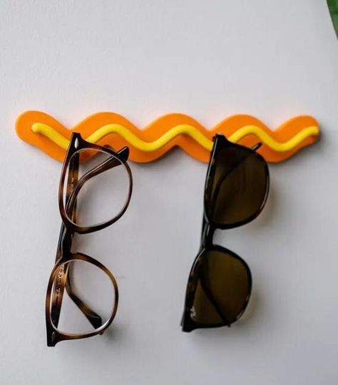 Introducing the Ripple Rack - a sleek and stylish sunglasses holder designed to keep your accessories organized and within reach. Made from durable PLA, the Ripple Rack holds up to 4 pairs of sunglasses, jewelry, or other lightweight, hangable items. Its modern wavy design adds a touch of elegance to any space, and it's available in a variety of vibrant colors to match your decor. Perfect for home or office, the Ripple Rack ensures your essentials are always neatly displayed and easy to find.  C Apartment Decor Funky, Wavy Decor, Sunglasses Organization, Sunglasses Wall, Sunglasses Rack, Glasses Organizer, Jewlery Holder, Colorful Sunglasses, Sunglasses Stand