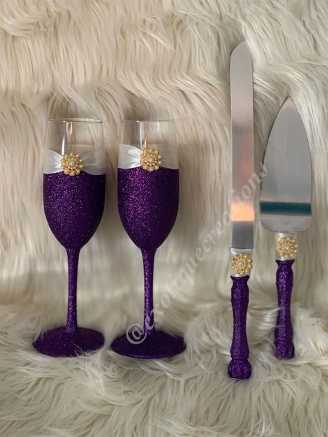 This Wedding Set includes a stainless steel cake server set and 2 champagne flutes. Purple Glitter with Ivory ribbon and a Gold with pearls brooch.  Perfect for your Purple and Ivory Wedding  Glitter has been sealed ..  Custom colors available ... Glasses stand about 9 inches tall Colors can be changed to match your wedding theme. Please ASK A QUESTION OR REQUEST A CUSTOM ORDER. Discount offered for huge quantities.  Please allow up to 6 business days for delivery for multiple quantities .  Made Purple And Gold Prom Decorations, Purple And Gold Wedding Centerpieces, Rose Gold And Purple Wedding, Purple Centerpiece Wedding, Purple And Rose Gold Wedding, Purple And Gold Wedding Theme, Purple And Gold Wedding Cake, Purple Wedding Reception Decorations, Purple Wedding Cupcakes