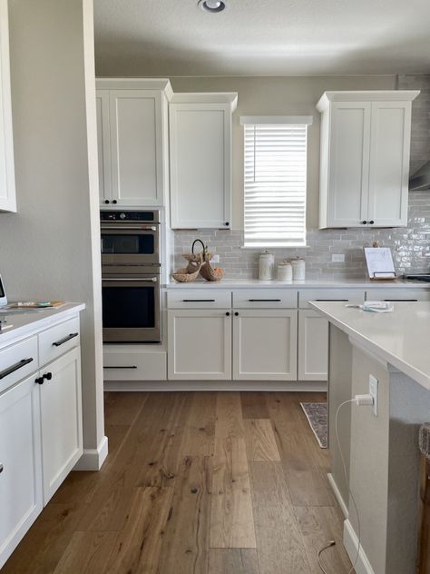 A kitchen painted with SW Accessible Beige and SW Pure White cabinets. Learn all about Accessible Beige in this paint color review. White Cabinet Beige Walls, Accessible Beige Whole House Color Scheme, Accessible Beige Sherwin Williams Color Scheme, Accessible Beige Walls With White Cabinets, Accessible Beige Sherwin Williams Kitchen Walls, White Kitchen Cabinets Beige Walls, Beige Kitchen Walls White Cabinets, Accesible Beige Sherwin Williams Kitchen Cabinets, Accessible Beige With Alabaster Trim