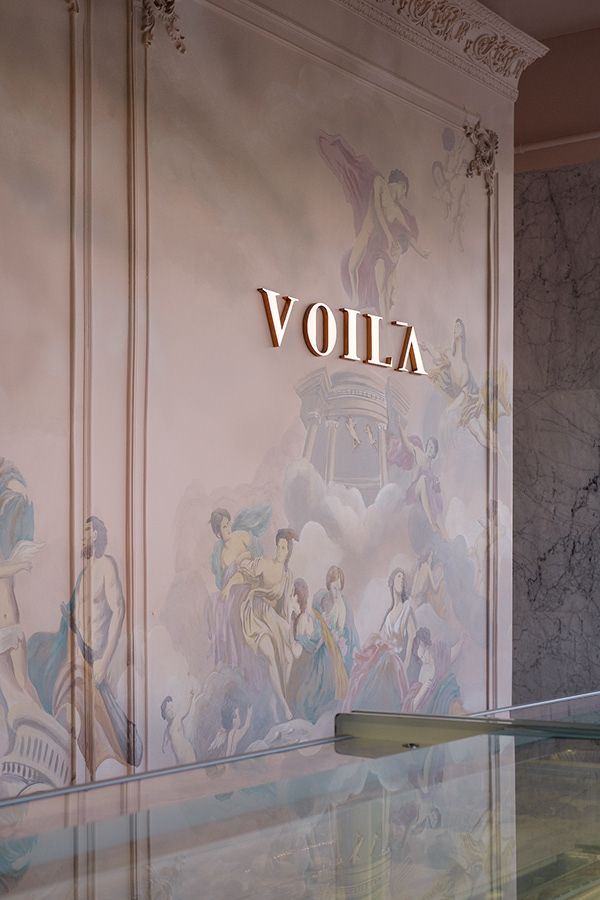 the word volla is written in gold on a wall painted with images of women and men