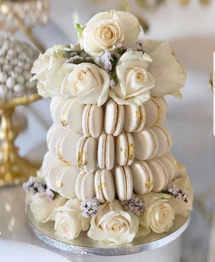 a wedding cake with macaroons and roses on top is shown in this image