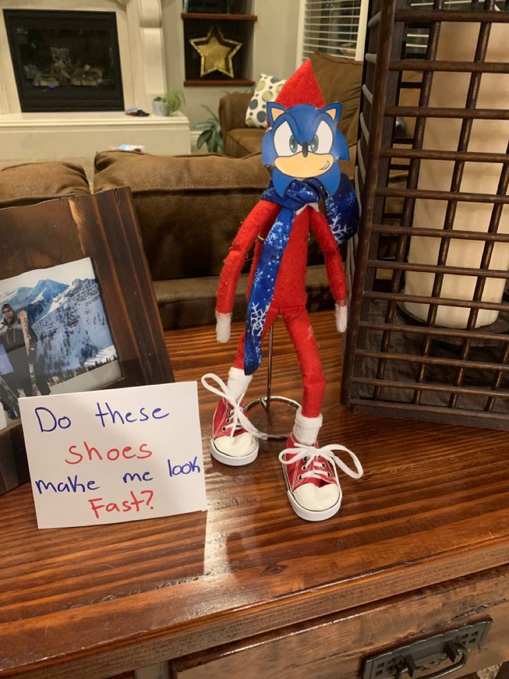 a red and blue stuffed animal sitting on top of a wooden table next to a sign that says do these shoes make me look fast?