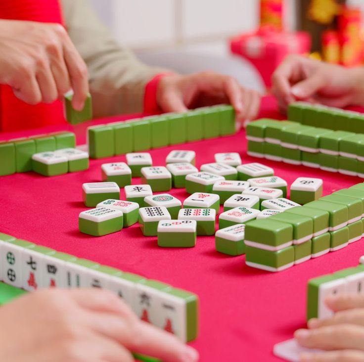 people playing with dominos on a pink table