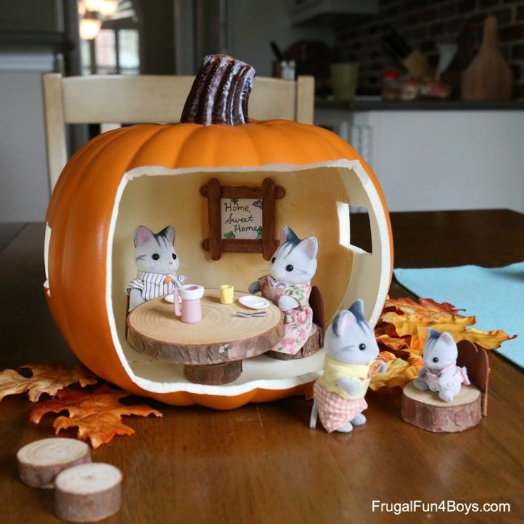 an orange pumpkin shaped like a house with mice sitting around it on top of a wooden table