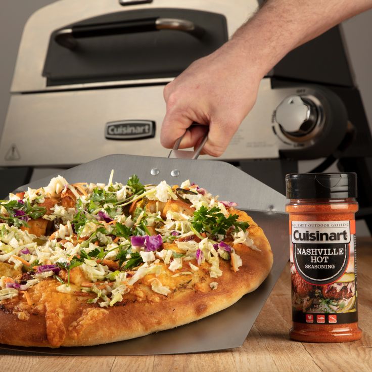 a person cutting up a pizza on top of a wooden table