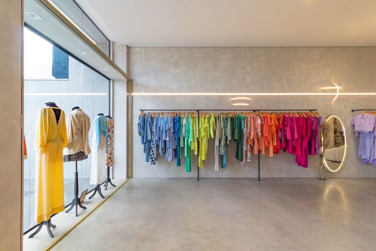 a clothing store with colorful shirts hanging on the wall and mirrors in front of it