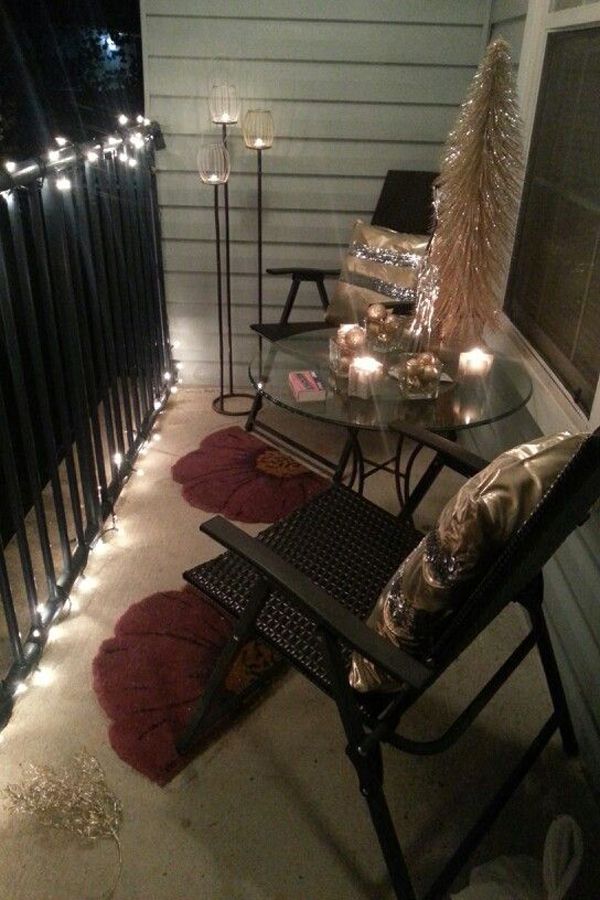 a balcony with christmas lights on the railings and candles lit up in front of it