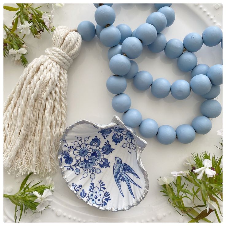 a plate with blue beads and tassels on it next to a white bead necklace