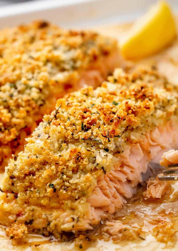 a piece of salmon covered in parmesan on a white plate with a fork