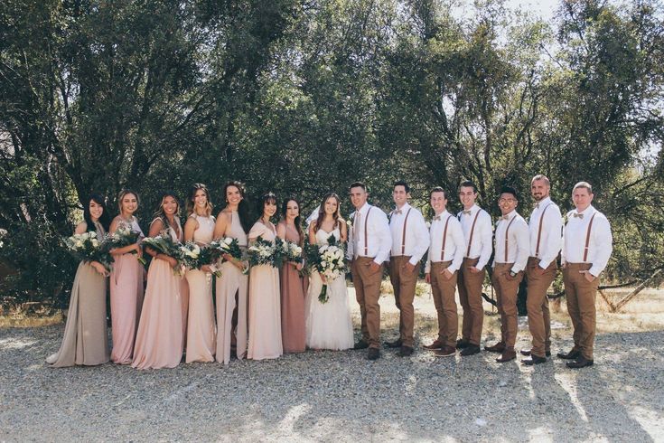 a group of people standing next to each other in front of some trees and bushes