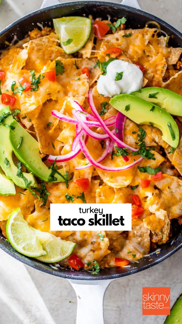 a skillet filled with chicken, cheese and veggies next to sliced avocado