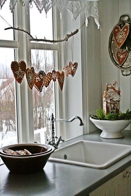 a kitchen sink sitting under a window next to a white bowl filled with cookies on top of a counter