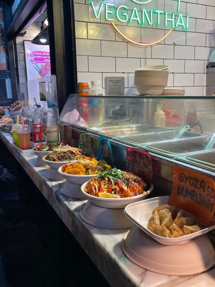 several bowls of food are lined up on the counter in front of a veggie shop