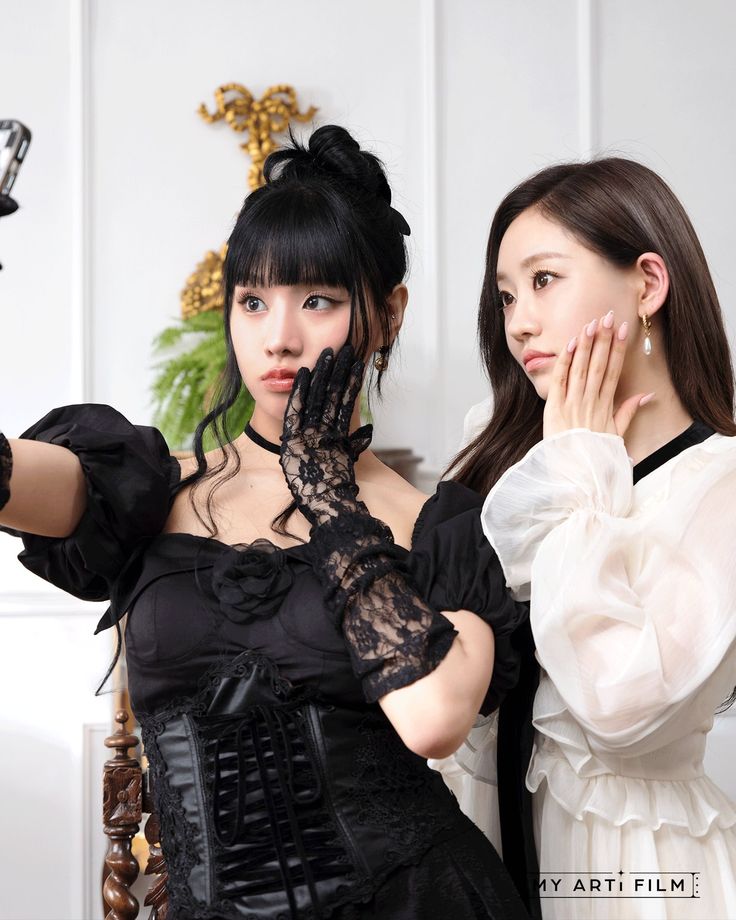 two young women dressed in black and white posing for the camera with their hands on their face