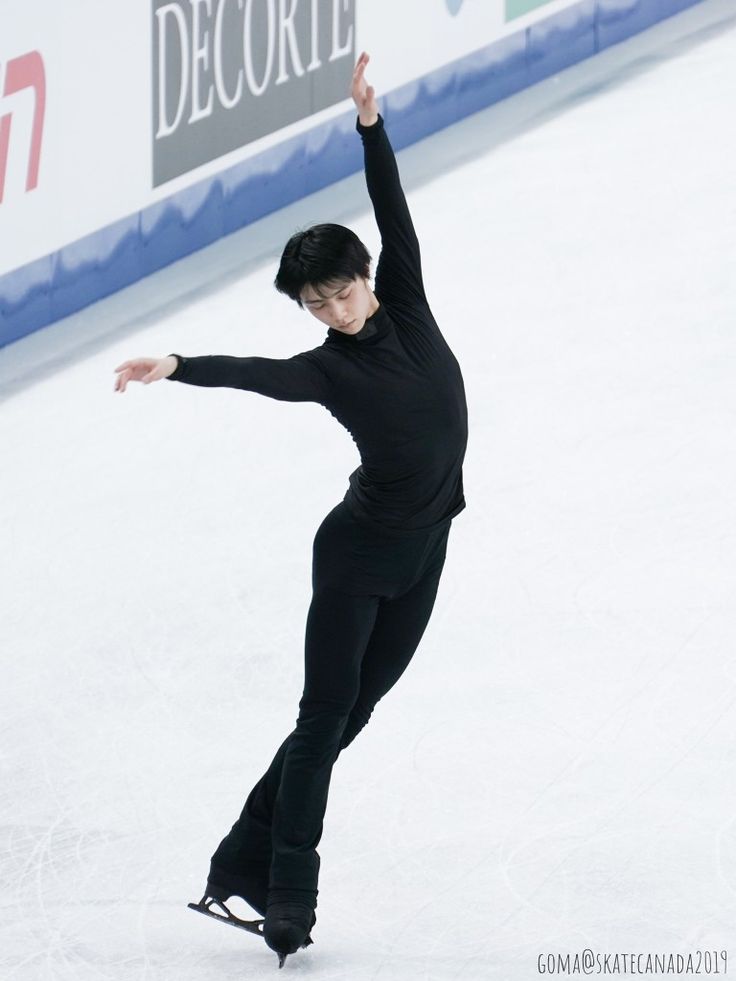 a male figure skating on an ice rink with his arms in the air and one hand up