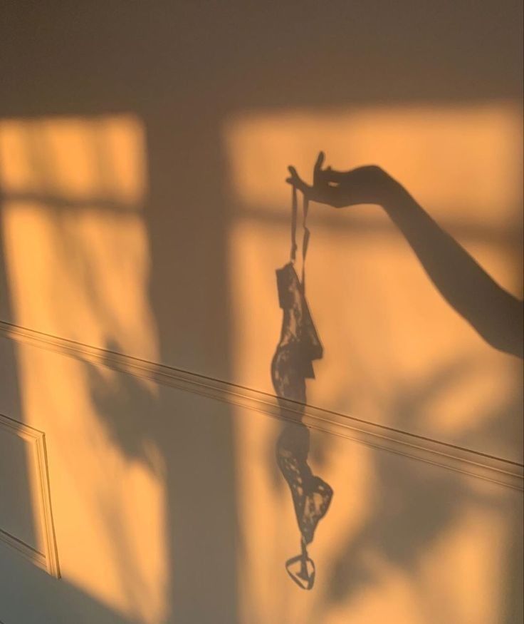 the shadow of a person's hand hanging from a string