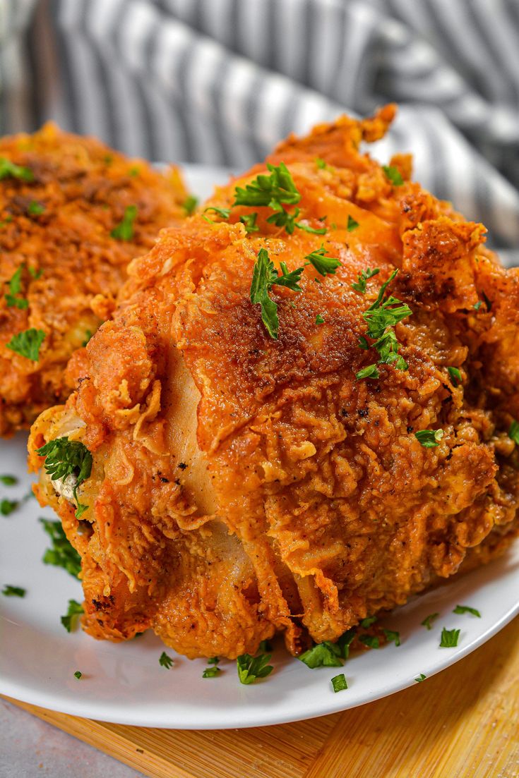 two fried chicken on a white plate with parsley