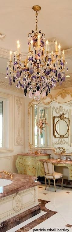 a fancy bathroom with chandelier, vanity and mirror in the middle of it