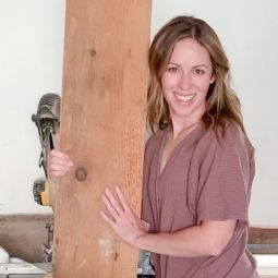 a woman standing next to a wooden board