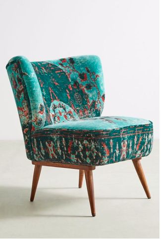 an upholstered chair with wooden legs and floral fabric on the armrests