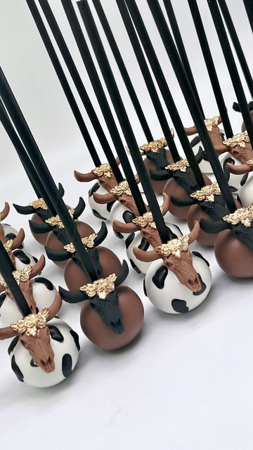 there are many chocolates in the shape of cows on top of eggs with black sticks sticking out of them