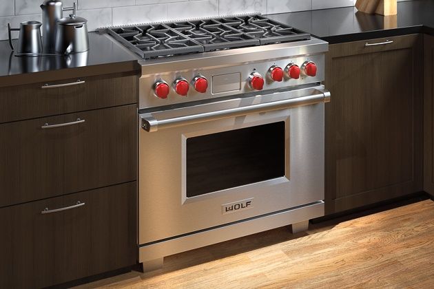 a stainless steel stove top oven sitting in a kitchen next to wooden cabinets and counter tops