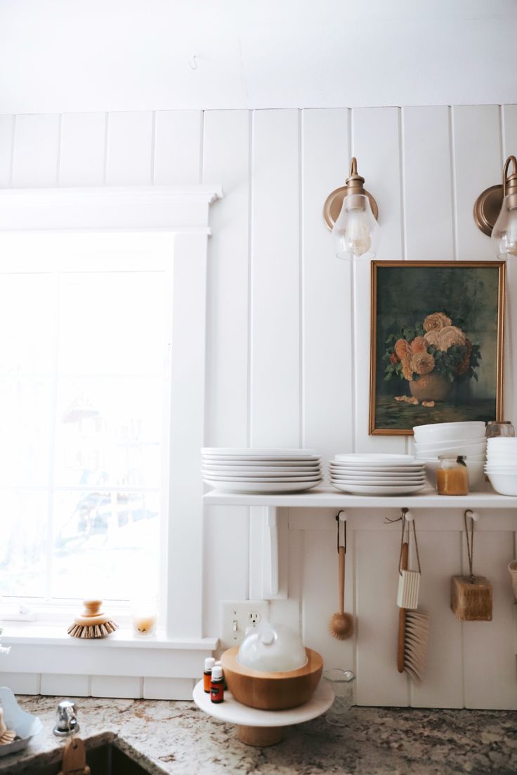 a kitchen counter with plates and utensils hanging on the wall next to a window