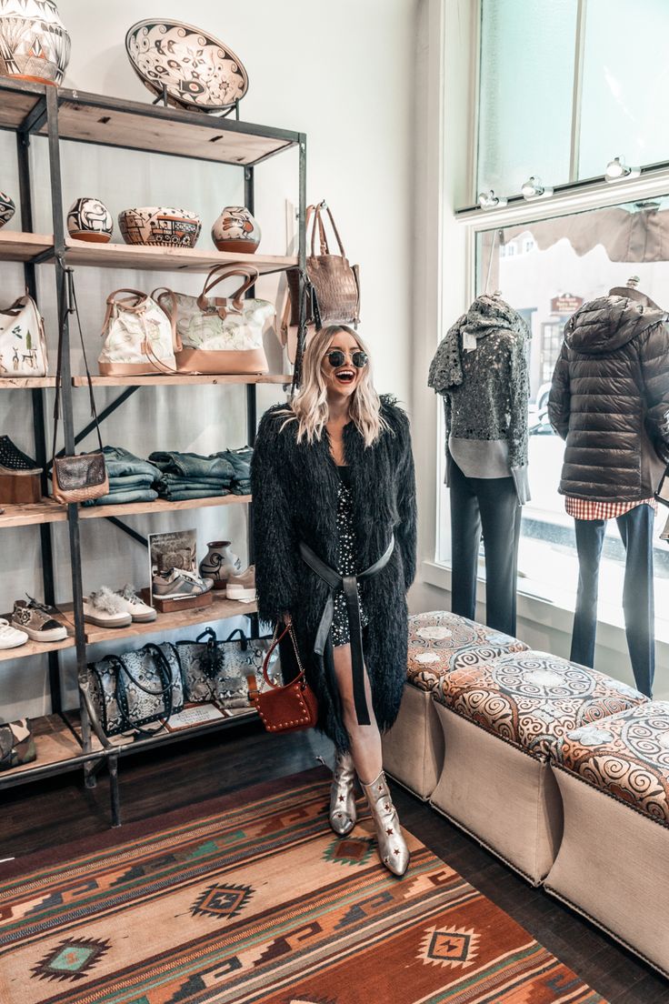 a woman sitting on a bench in front of a display of handbags and purses